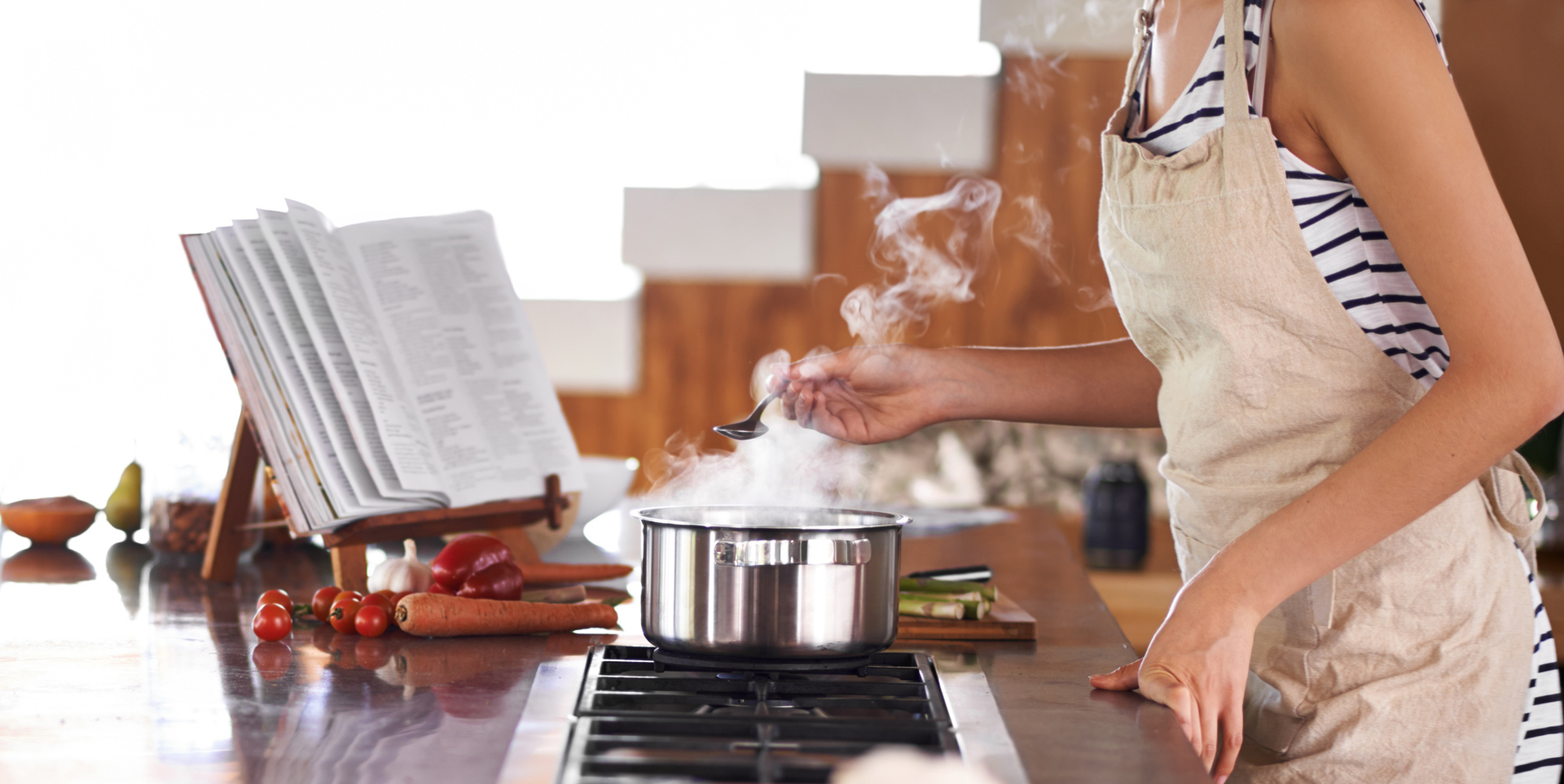 A person stood at their hob stirring a steaming pan