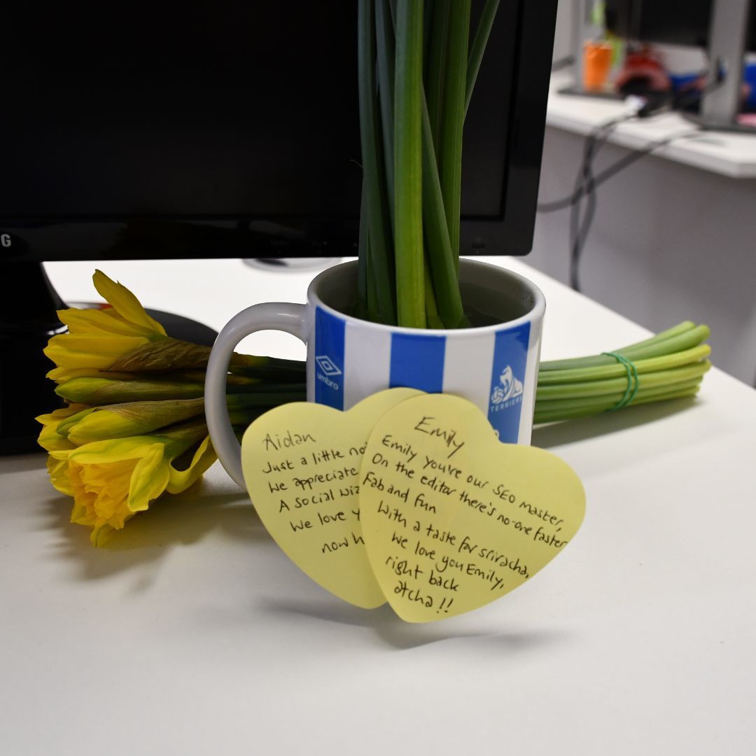 Flowers in a cup with yellow sticky notes attached.