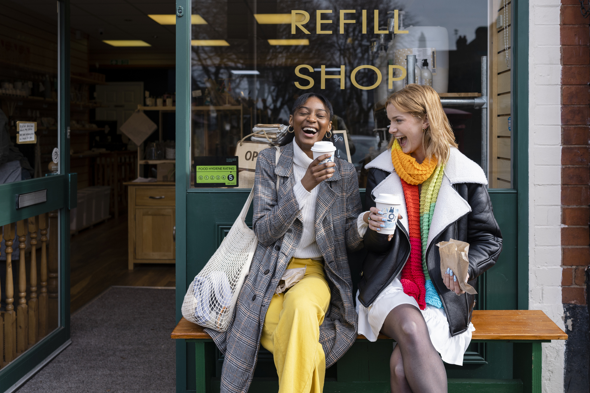 Two friends sitting outside a store that promotes sustainable living in the North East of England.