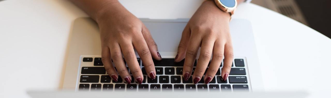 A close up of a woman's hands typing on a keyboard