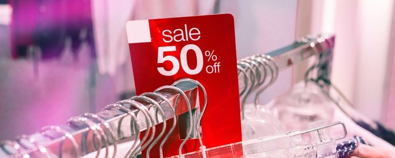 A shop's reduced price rack with a red sale sign stating 50 percent reduced